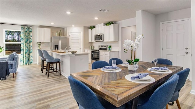 dining space with light hardwood / wood-style flooring and a textured ceiling