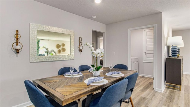 dining space with light hardwood / wood-style flooring and a textured ceiling