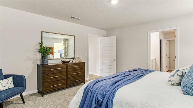 carpeted bedroom featuring ensuite bath and a textured ceiling