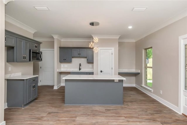 284 Magnolia Dr, Mobile, AL 36617 - kitchen with stainless steel microwave, wood finished floors, a kitchen island, gray cabinets, and crown molding