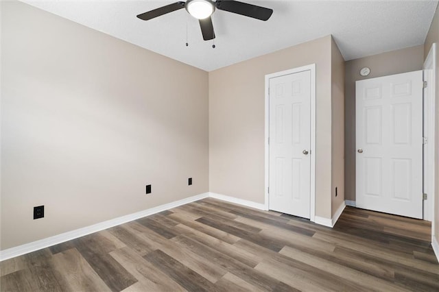 unfurnished bedroom with ceiling fan and dark hardwood / wood-style flooring