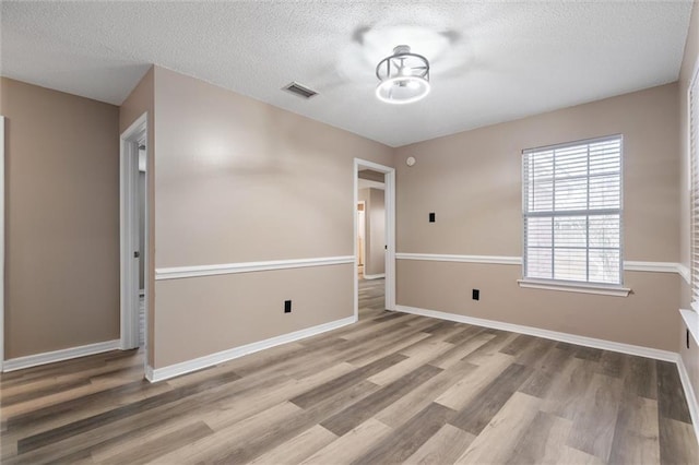 unfurnished room with hardwood / wood-style flooring and a textured ceiling