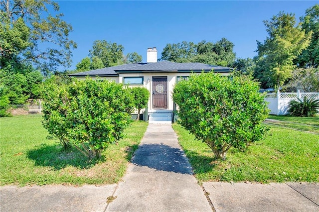 bungalow with a chimney, driveway, a front yard, and fence