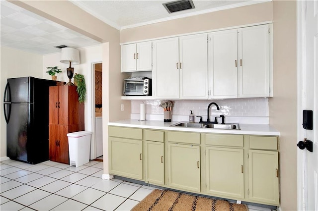 kitchen featuring a sink, visible vents, freestanding refrigerator, and green cabinetry