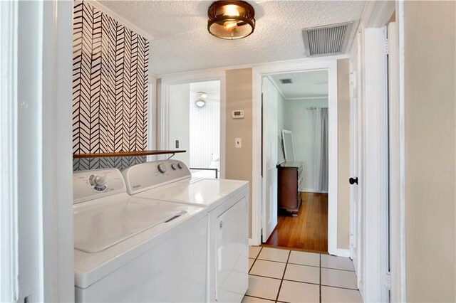 clothes washing area featuring independent washer and dryer, a textured ceiling, light tile patterned floors, and visible vents