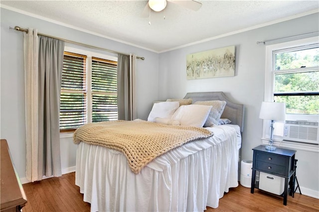 bedroom featuring ceiling fan, cooling unit, ornamental molding, a textured ceiling, and hardwood / wood-style floors