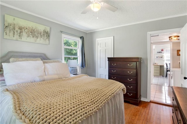bedroom with crown molding, ceiling fan, a textured ceiling, a closet, and wood finished floors