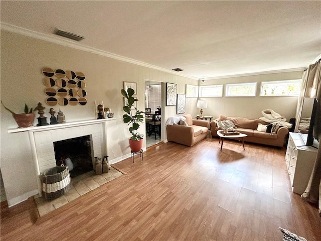 living room featuring wood-type flooring, a fireplace, and crown molding