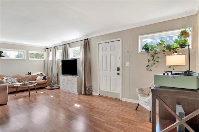 living area with wood finished floors, baseboards, and ornamental molding