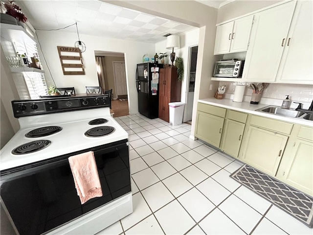 kitchen with black fridge, electric stove, light tile patterned floors, and sink