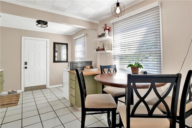 dining room featuring light tile patterned floors, baseboards, ornamental molding, and a healthy amount of sunlight