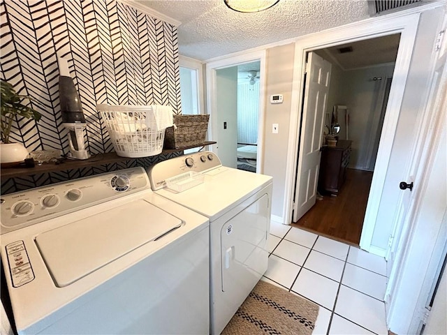 clothes washing area with ornamental molding, washer and dryer, light tile patterned floors, and a textured ceiling