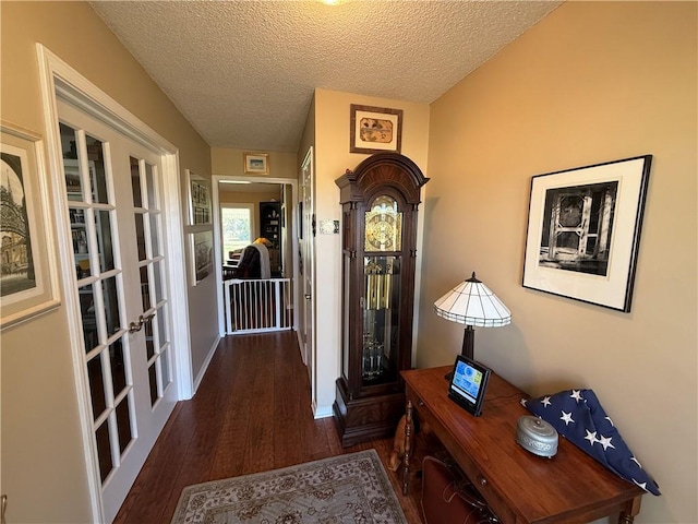 interior space featuring wood finished floors, baseboards, french doors, and a textured ceiling