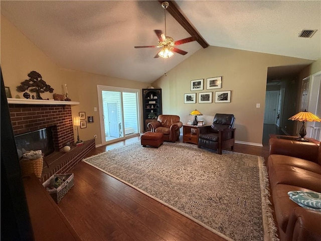 living room with visible vents, a textured ceiling, wood finished floors, a fireplace, and vaulted ceiling with beams