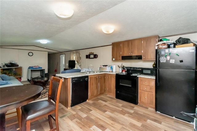 kitchen with kitchen peninsula, black appliances, a textured ceiling, and light wood-type flooring