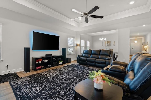 living room featuring hardwood / wood-style floors, ceiling fan with notable chandelier, a tray ceiling, and crown molding