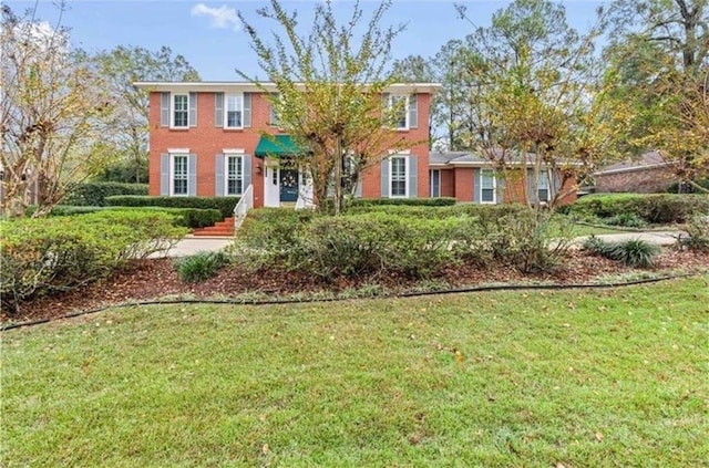 colonial house with a front yard and brick siding