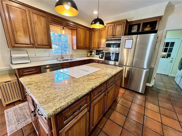 kitchen featuring appliances with stainless steel finishes, a center island, light stone countertops, crown molding, and a sink