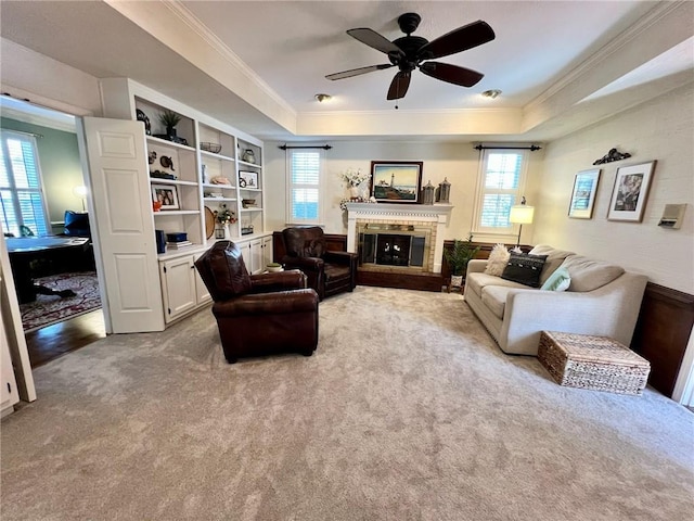 carpeted living area with a healthy amount of sunlight, crown molding, and a glass covered fireplace