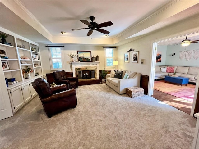 living area featuring a tray ceiling, a brick fireplace, carpet flooring, and crown molding