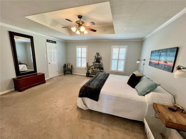 bedroom with light carpet, a ceiling fan, baseboards, a tray ceiling, and crown molding