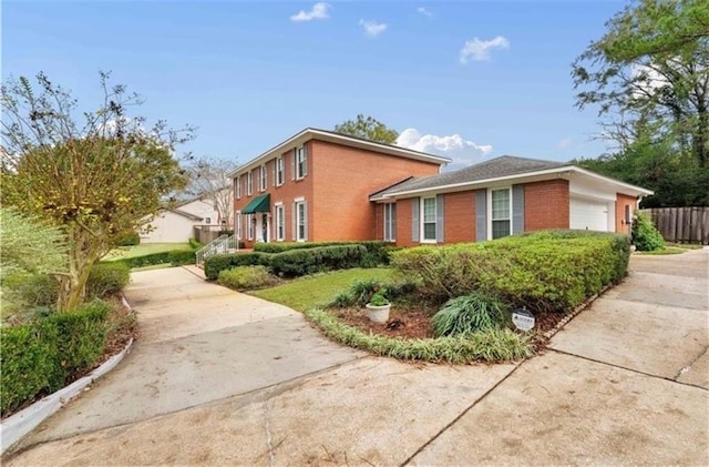 view of home's exterior featuring an attached garage, fence, concrete driveway, and brick siding