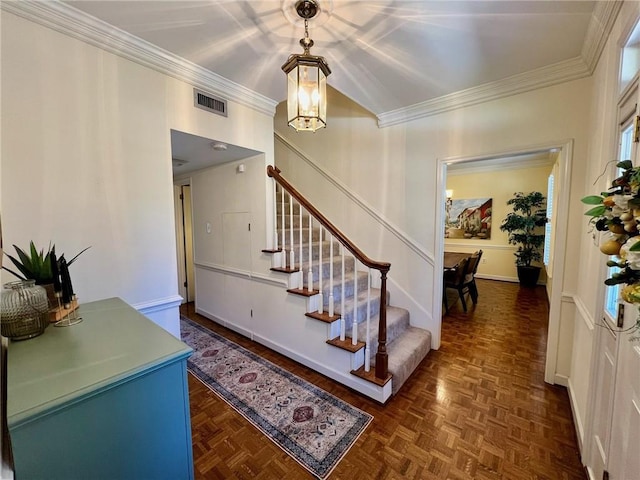 interior space with baseboards, a chandelier, visible vents, and crown molding