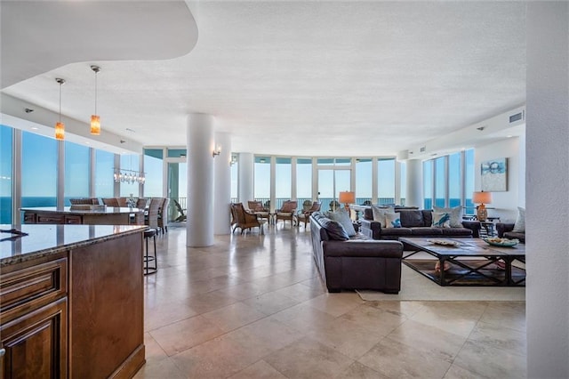tiled living room with an inviting chandelier, floor to ceiling windows, and a water view