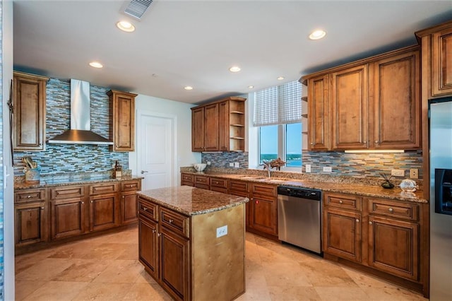 kitchen with light stone countertops, backsplash, appliances with stainless steel finishes, a center island, and wall chimney exhaust hood