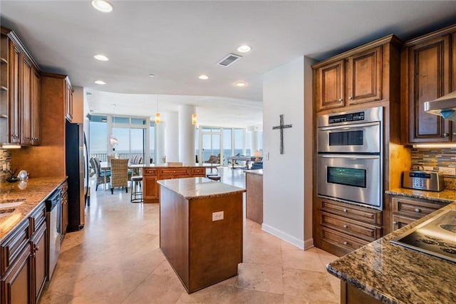 kitchen featuring light tile flooring, backsplash, a kitchen island, and appliances with stainless steel finishes