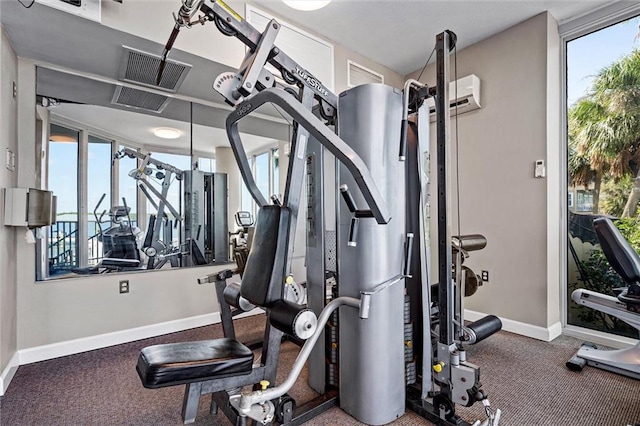 gym featuring a wall mounted air conditioner and dark colored carpet