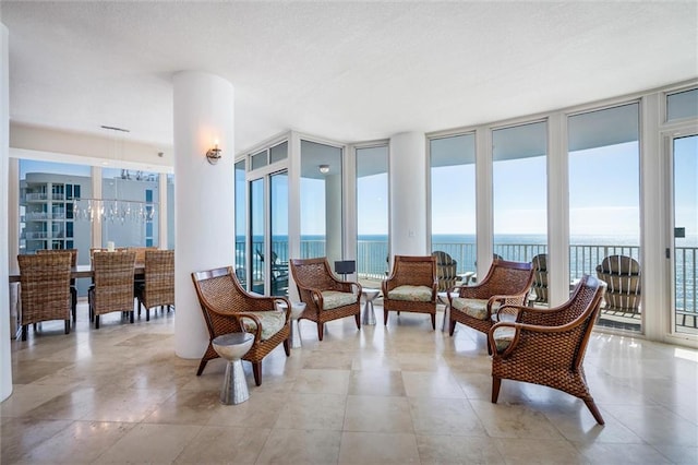 living area featuring a water view, a wall of windows, and light tile floors