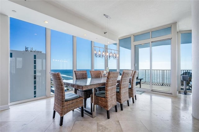 tiled dining room with expansive windows, a water view, and a notable chandelier