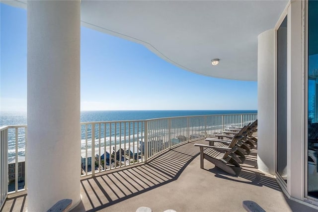balcony with a water view and a view of the beach