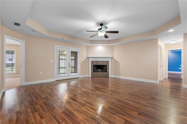unfurnished living room featuring ceiling fan, visible vents, a wealth of natural light, and a raised ceiling