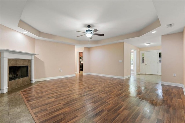 unfurnished living room featuring ceiling fan, visible vents, a raised ceiling, baseboards, and recessed lighting