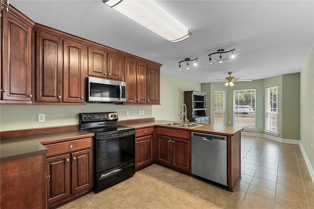 kitchen with a ceiling fan, appliances with stainless steel finishes, dark countertops, a sink, and a peninsula