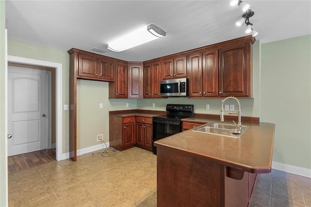 kitchen with black range with electric stovetop, a sink, baseboards, stainless steel microwave, and a peninsula