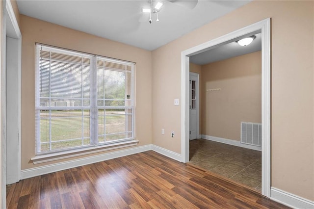 unfurnished room featuring ceiling fan, visible vents, dark wood-style floors, and baseboards