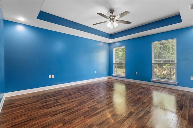 unfurnished room with ceiling fan, a raised ceiling, baseboards, wood finished floors, and visible vents