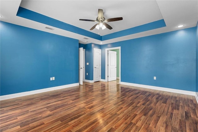 empty room featuring baseboards, visible vents, ceiling fan, and a raised ceiling