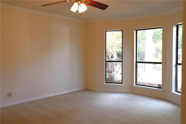 carpeted spare room featuring a wealth of natural light, ornamental molding, and ceiling fan