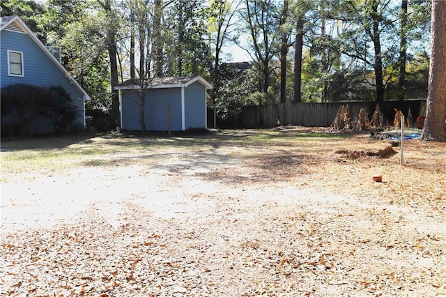 view of yard featuring a storage shed, fence, and an outbuilding