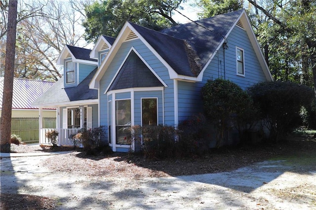 view of front of property featuring fence, a shingled roof, and a porch