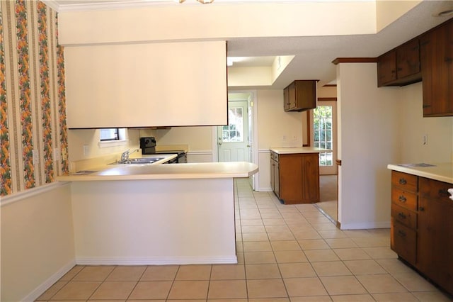 kitchen with light tile patterned flooring, sink, dark brown cabinets, kitchen peninsula, and range with electric cooktop