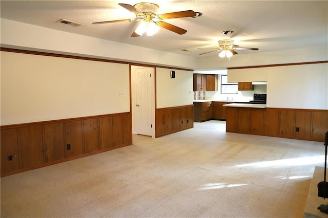 kitchen with black / electric stove, light carpet, a textured ceiling, and kitchen peninsula