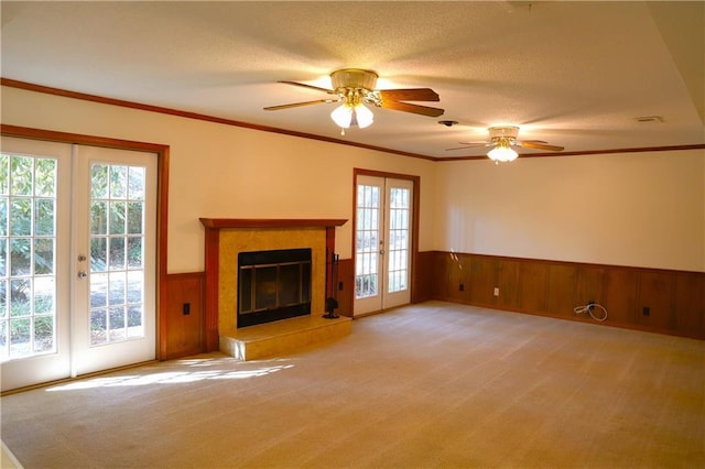 unfurnished living room featuring french doors, crown molding, light carpet, a textured ceiling, and ceiling fan