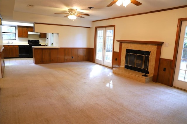 unfurnished living room featuring a premium fireplace, plenty of natural light, ornamental molding, and light carpet