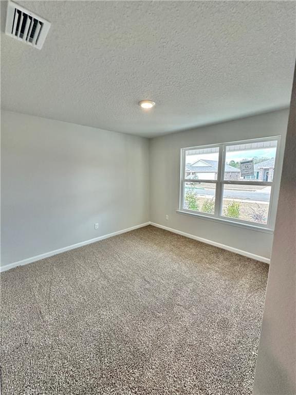 carpeted empty room featuring a textured ceiling