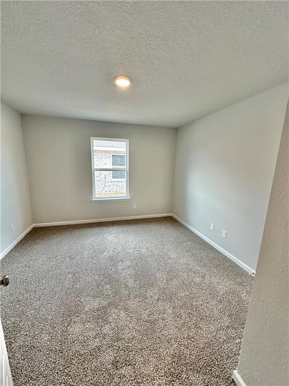 carpeted empty room featuring a textured ceiling